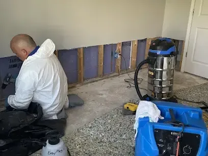 Wet drywall cut out with a dehumidifier running during a dry-out